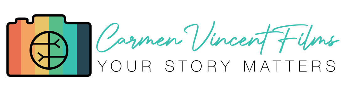Carmen Vincent Films Logo: An outline of a camera with colors red, orange, yellow, green, blue, and navy blue inside of it. The lens is represented by the symbol for empathy, which is two arms reaching to each other's side. Next to the camera, in blue text, reads 